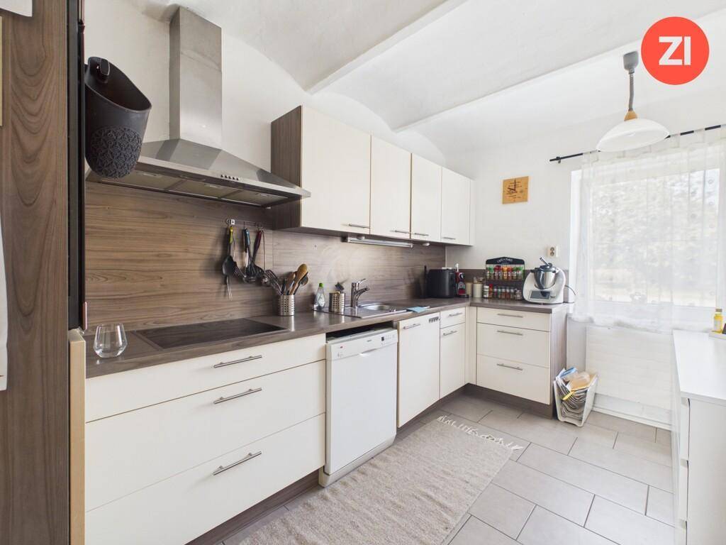 Funktionale Küche mit weißen Schränken, Holzdetails und integrierten Geräten.