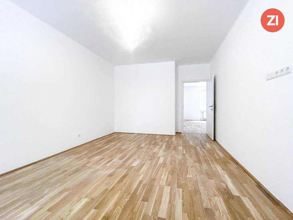 Freundlicher Raum mit hellem Parkettboden und weiß gestrichenen Wänden, ideal für ein Schlafzimmer.