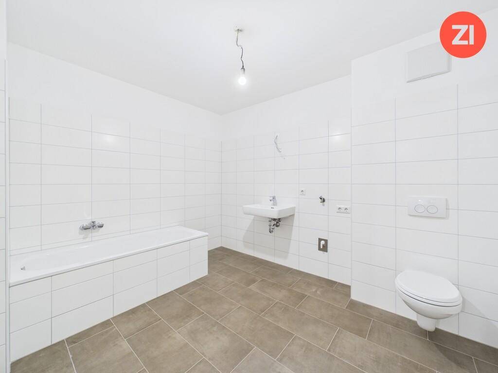 Modernes Badezimmer mit weißen Fliesen, einer Badewanne, einem wandhängenden WC und einem Waschbecken.