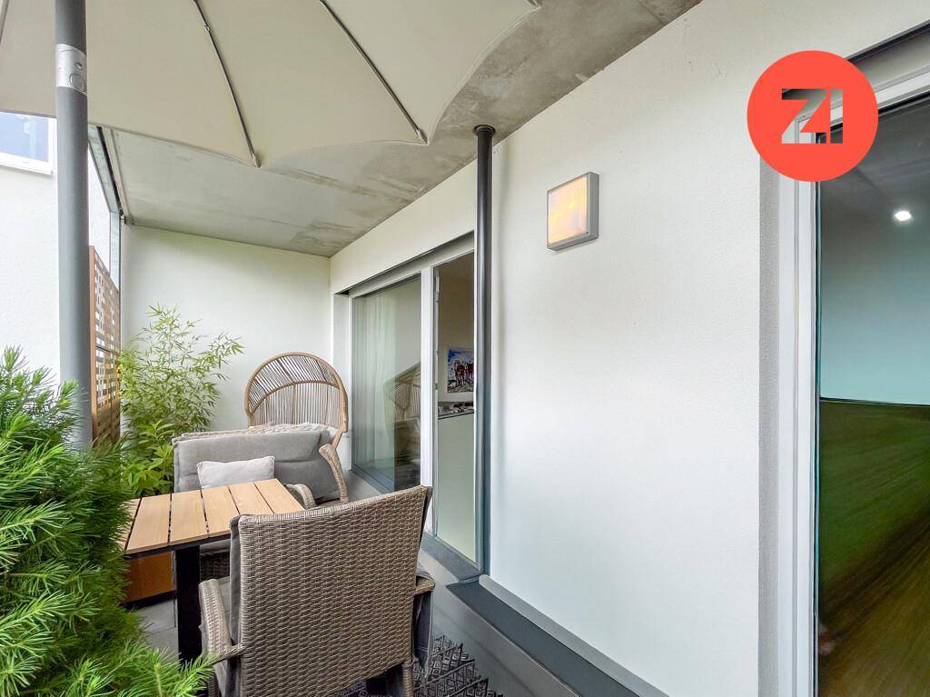 Gemütlicher Balkon mit Sitzgelegenheiten, Sonnenschirm und Pflanzen für entspannte Stunden.