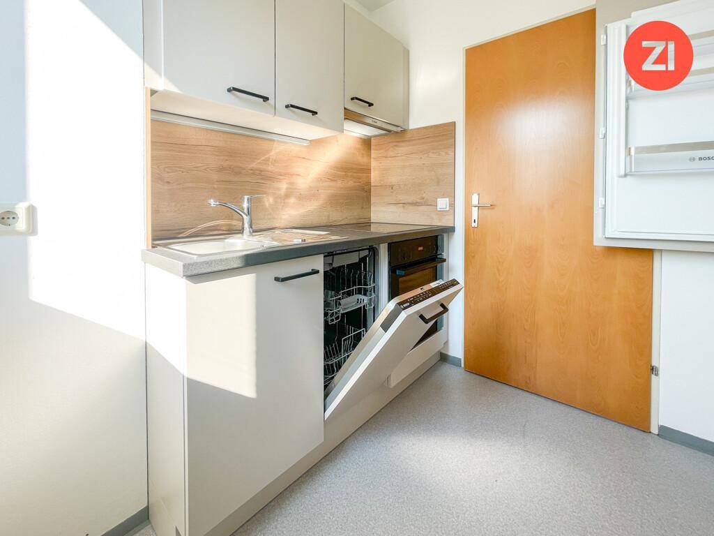 Moderne Küchenzeile mit Spülmaschine, Spüle und Holzrückwand in einem hellen Raum.