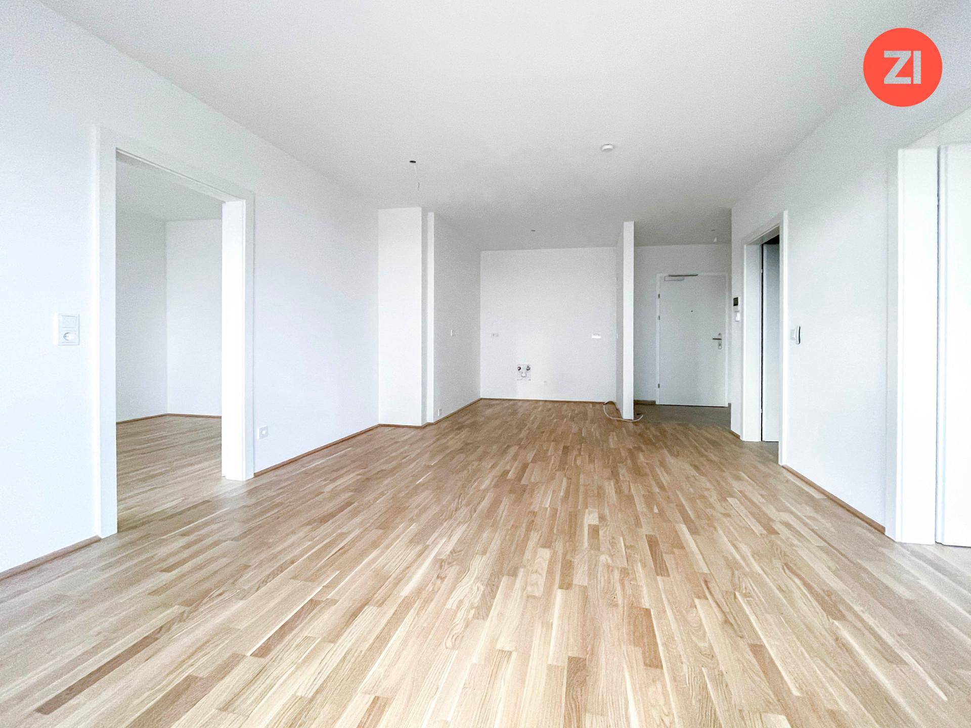 Heller, leerer Wohnbereich mit neuem Holzparkettboden und weißen Wänden.