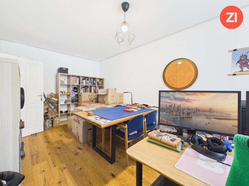 Geräumiges Büro mit Holzboden, mehreren Arbeitsplätzen und viel Stauraum in Regalen.