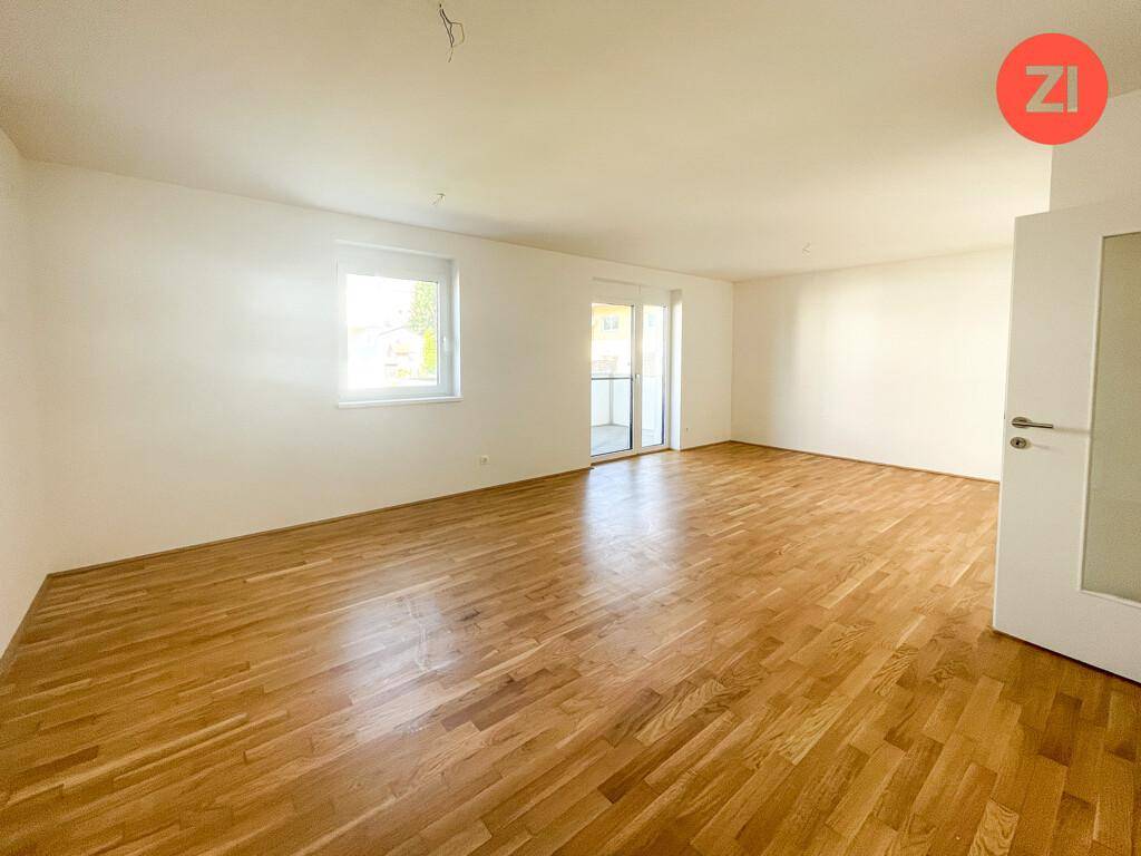 Geräumiges, helles Wohnzimmer mit Eichenparkettboden, großem Fenster und Zugang zum Balkon.
