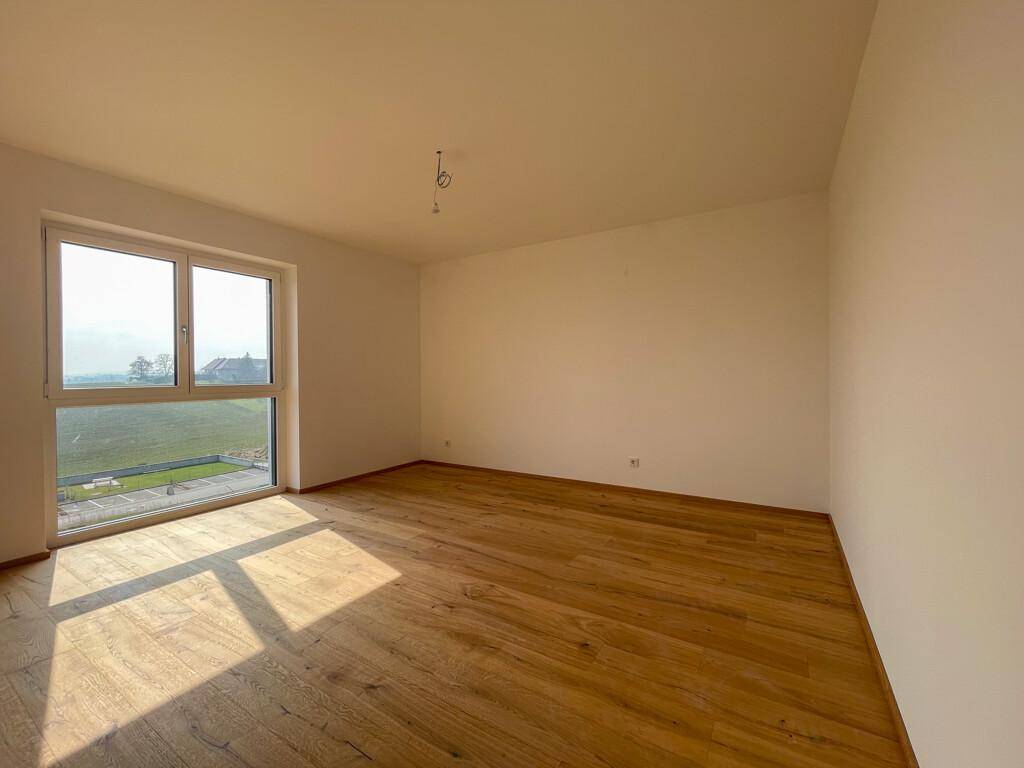 Helles Zimmer mit großem Fenster, Holzboden und viel Tageslicht.