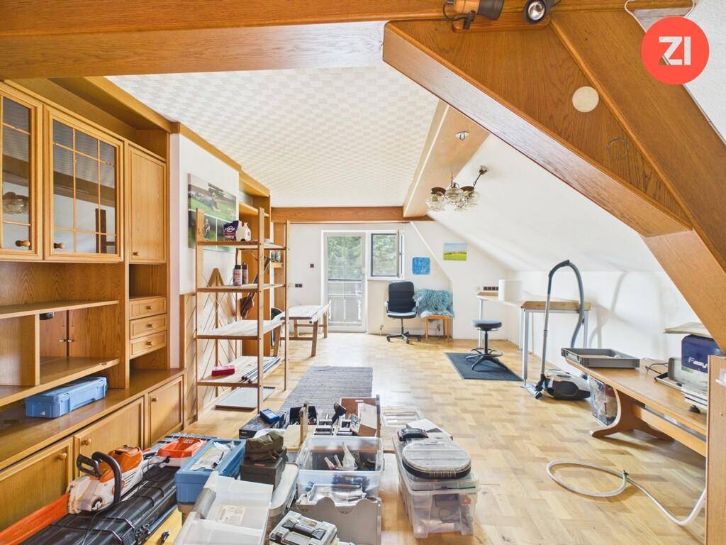 Ausgebauter Dachbodenbereich mit Holzvertäfelung, Stauraum und Dachfenster.