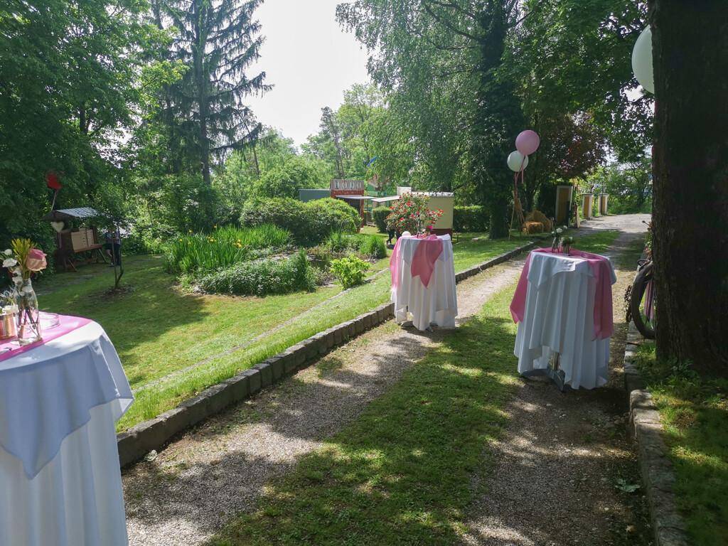 Gepflegter Gartenbereich mit Kiesweg und festlich dekorierten Stehtischen für Veranstaltungen.