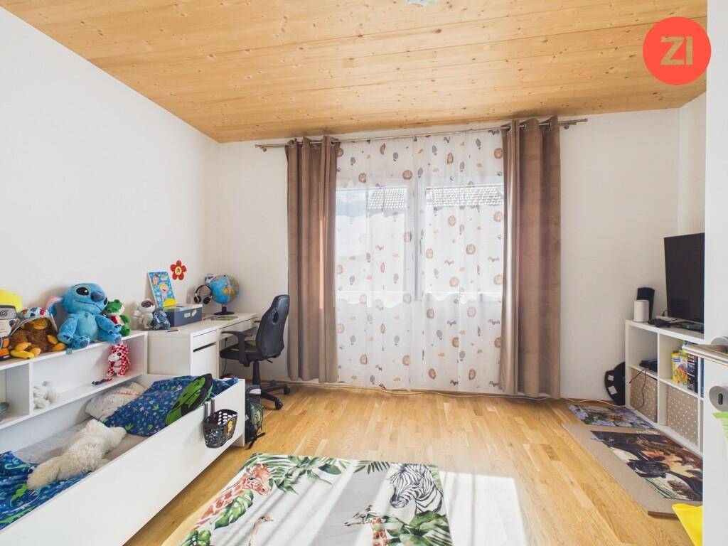 Helles Kinderzimmer mit Schreibtisch, Holzboden und braunen Vorhängen, bietet Platz zum Spielen.