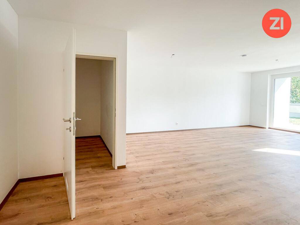 Großer, heller Raum mit Laminatboden und Zugang zu einem weiteren Bereich oder Flur.