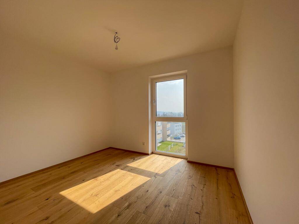 Lichtdurchflutetes Zimmer mit Holzboden und weitem Ausblick.