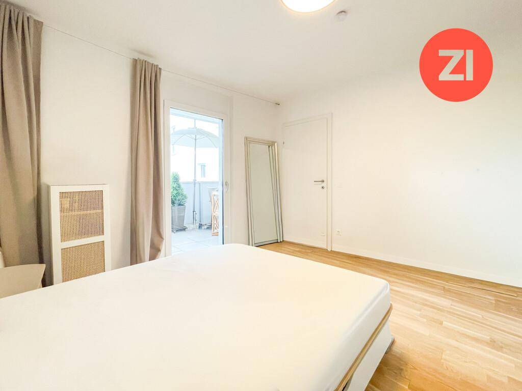 Helles Schlafzimmer mit Holzboden, großem Bett und Zugang zum Balkon.