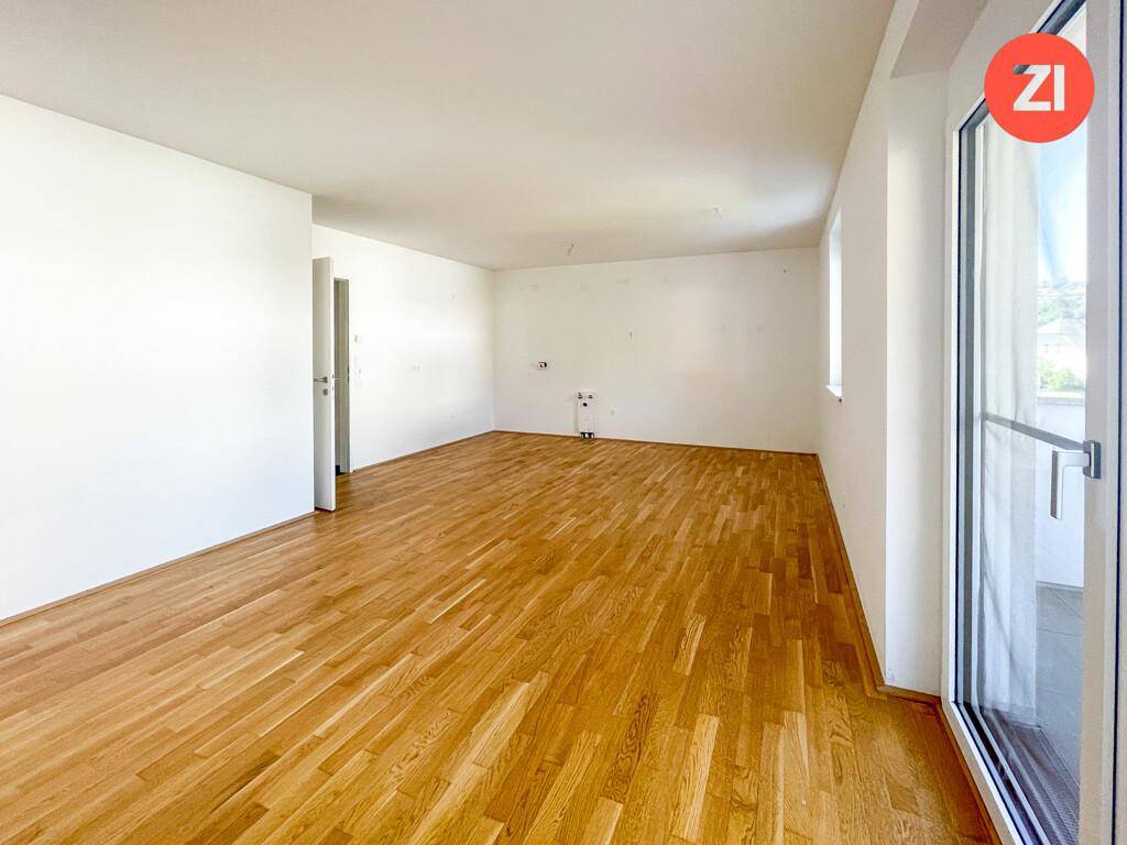 Heller Raum mit Eichenparkettboden und großem Fenster, möglicherweise für Wohn- oder Küchennutzung.