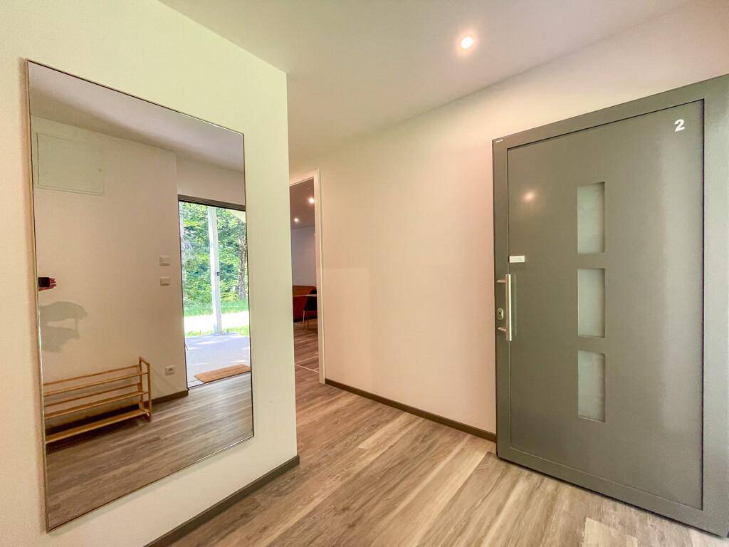 Heller Eingangsbereich mit großem Spiegel, Holzschuhregal und moderner Eingangstür.