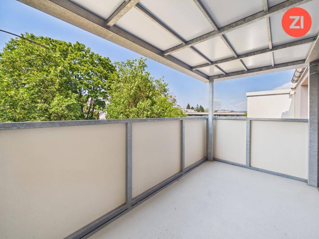 Überdachter Balkon mit Metallgeländer und Blick ins Grüne, ideal zum Entspannen.