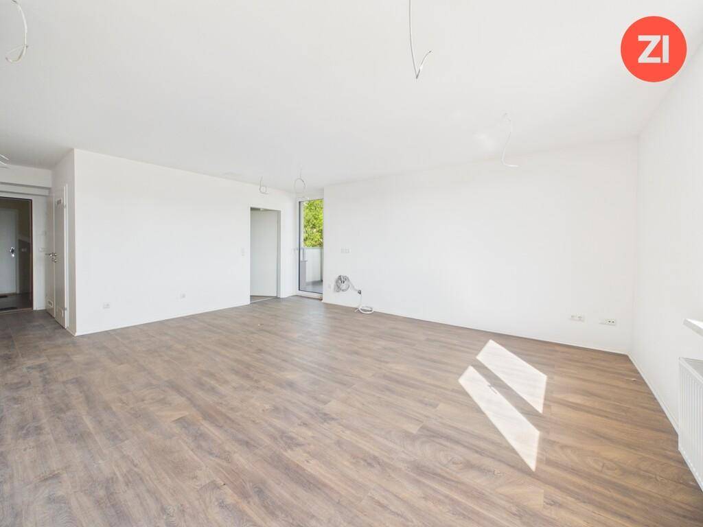Weitläufiger, heller Raum mit Holzboden und Zugang zu einem Außenbereich.