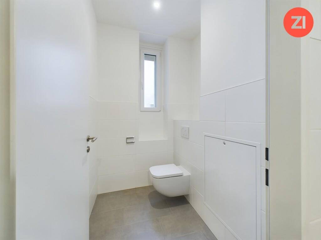 Modernes Gäste-WC mit wandhängender Toilette und kleinem Fenster, bietet Komfort und Privatsphäre.
