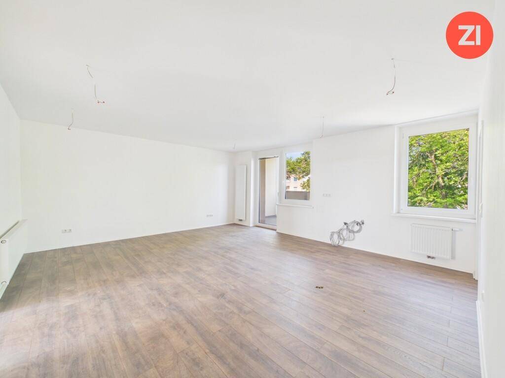 Geräumiges, helles Wohnzimmer mit Holzboden, großen Fenstern und Zugang zu einem Außenbereich.