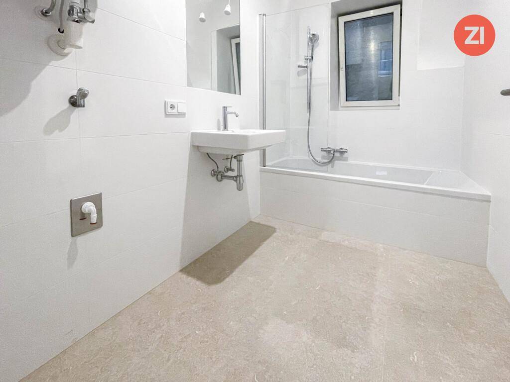 Modernes Badezimmer mit Badewanne, Duschfunktion, Waschbecken und einem Fenster für Tageslicht.