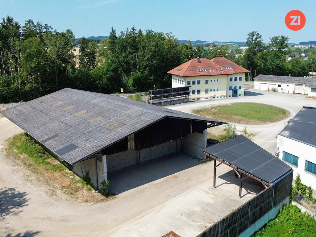 Luftaufnahme des Anwesens mit einem großen, offenen Lagergebäude und einem Carport, umgeben von viel Freifläche.