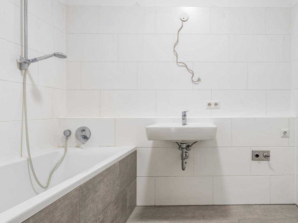 Helles Badezimmer mit Badewanne, Dusche und modernem Waschbecken.