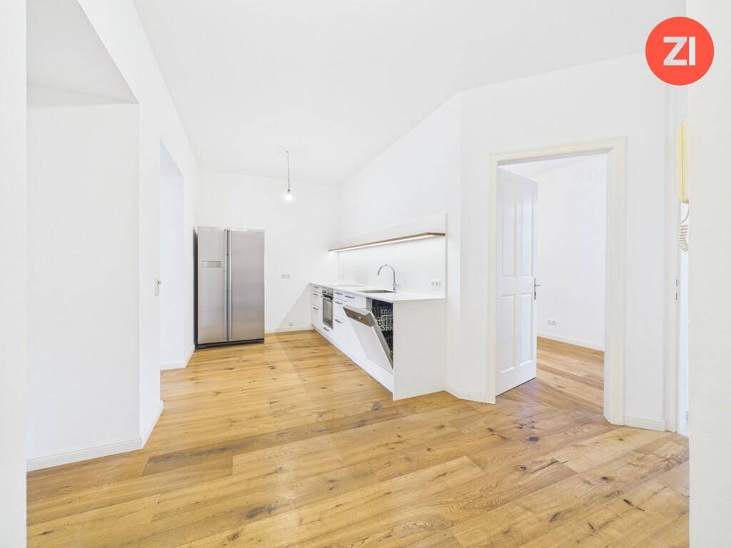 Moderne offene Küchenzeile mit Einbaugeräten, Edelstahlkühlschrank und viel Arbeitsfläche.