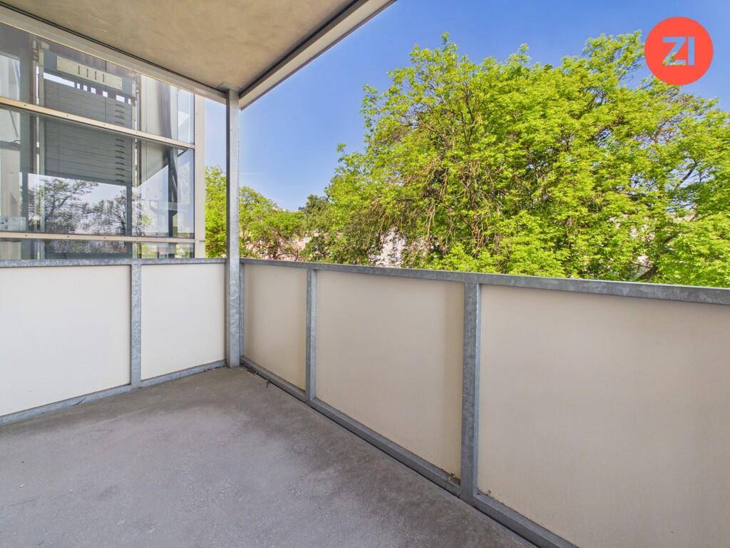 Heller Balkon mit seitlichem Blick auf Bäume und die Umgebung.