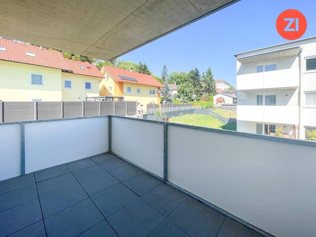 Geräumiger Balkon mit Fliesenboden und Blick auf die umliegende grüne Landschaft.