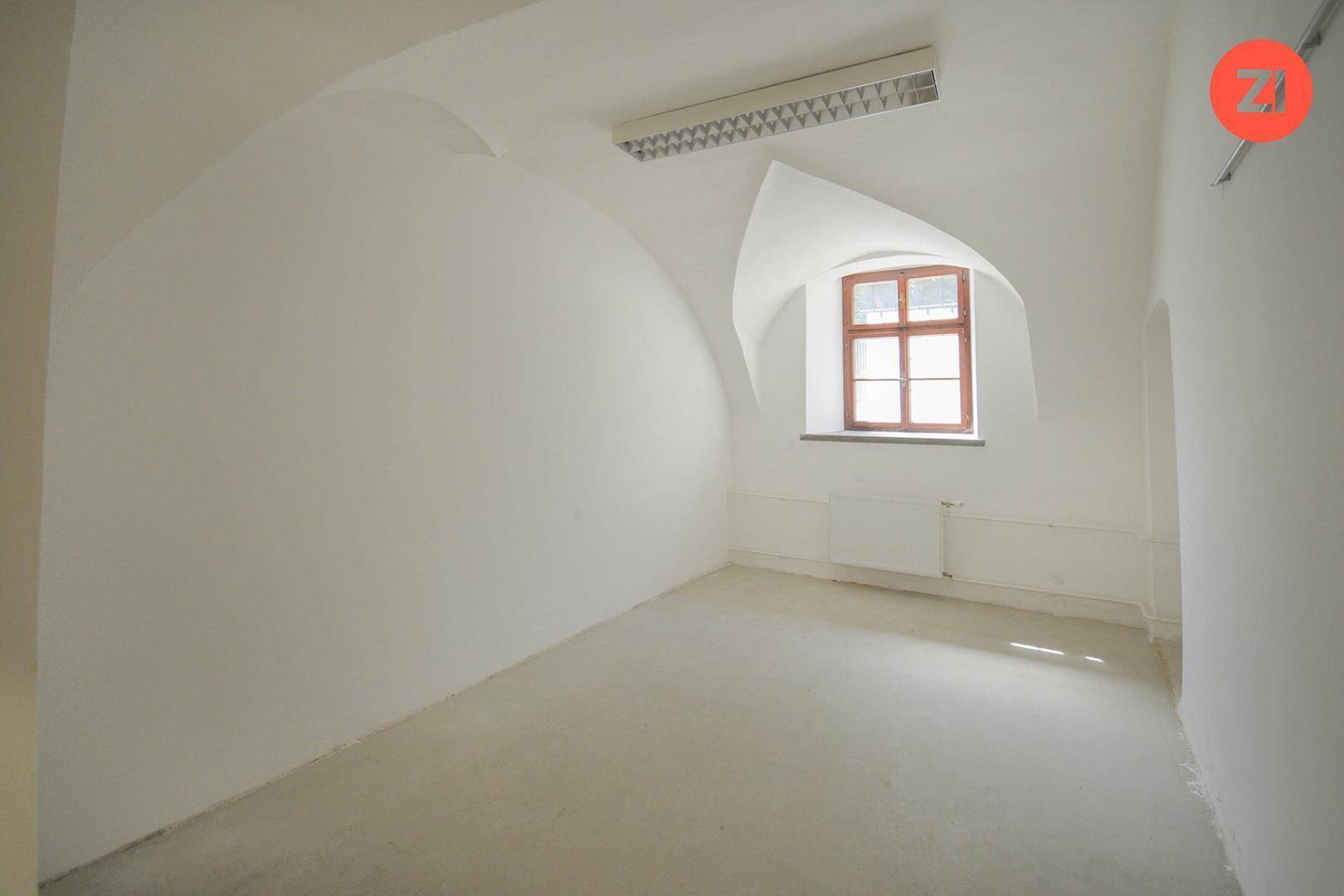 Leerer Raum mit gewölbter Decke, kleinem Fenster und Heizkörper, bereit für neue Nutzungskonzepte.