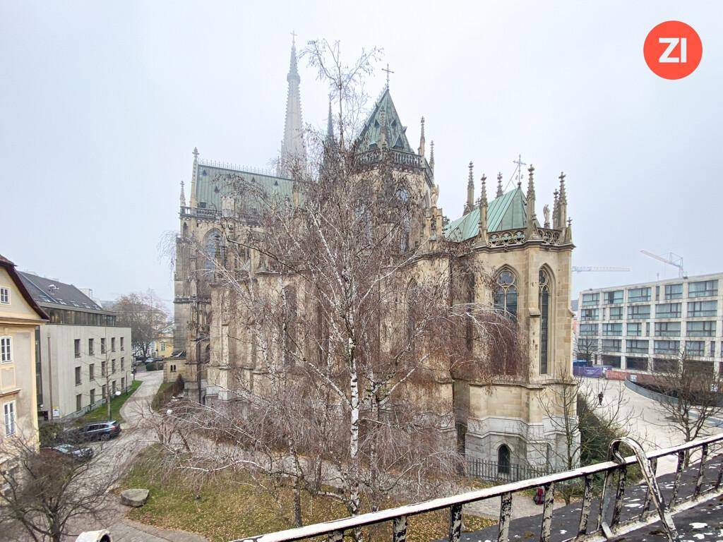 Weitläufiger Blick auf eine imposante Kathedrale und die umliegende Stadtlandschaft an einem bewölkten Tag.