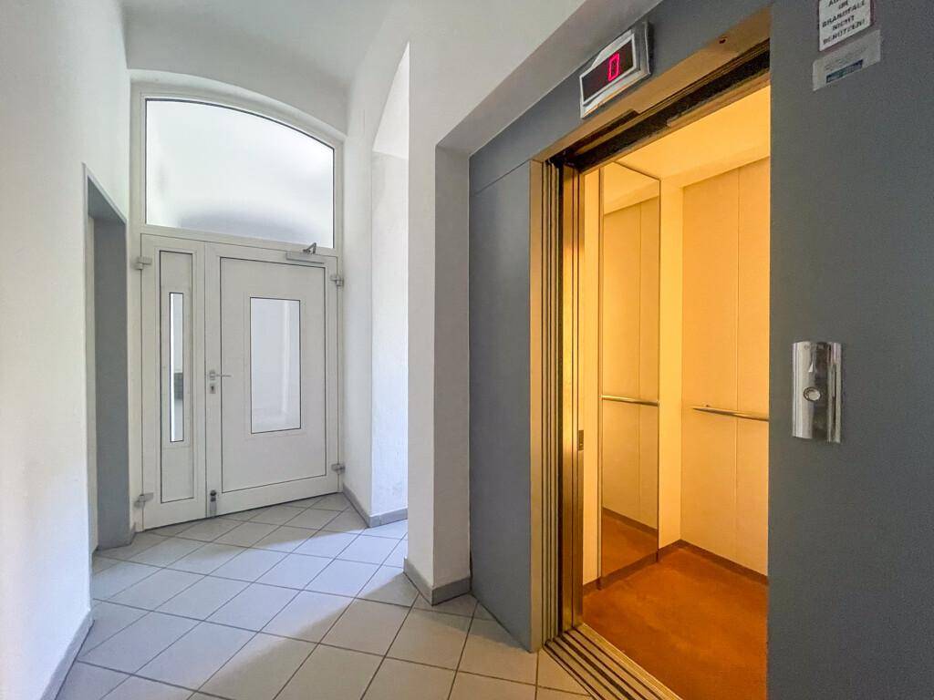 Eingangsbereich mit Fliesenboden und einem modernen Aufzug, der zu den oberen Etagen führt.