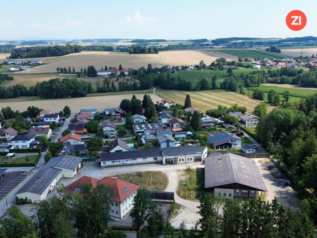 Weitläufige Luftaufnahme des Anwesens, eingebettet in eine ländliche Umgebung mit Feldern, Wäldern und einer kleinen Siedlung.