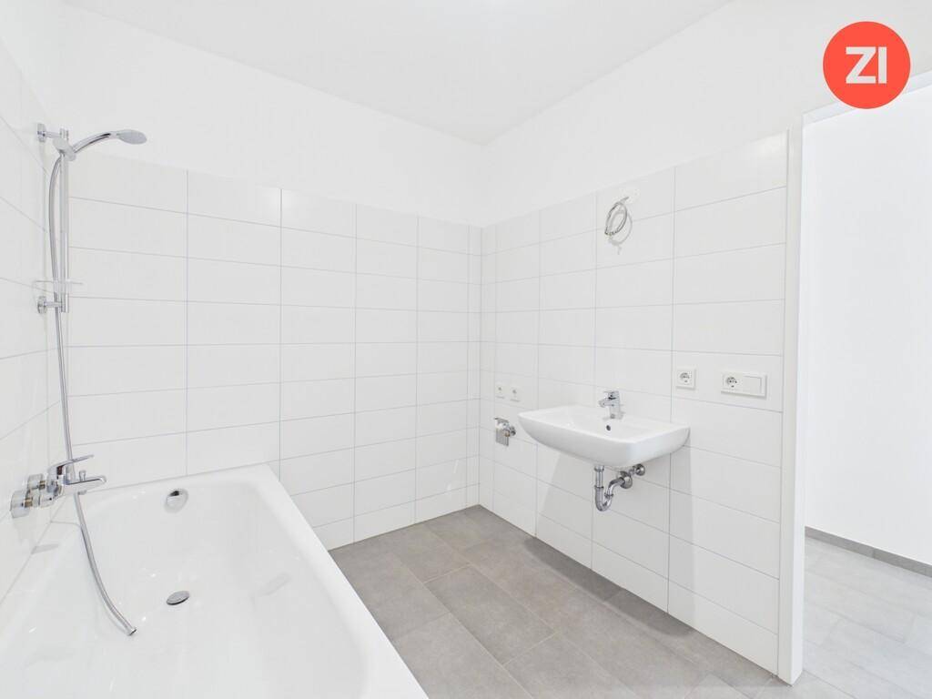 Modernes Badezimmer mit Badewanne, Waschbecken und weißen Wandfliesen, in einem gepflegten Zustand.