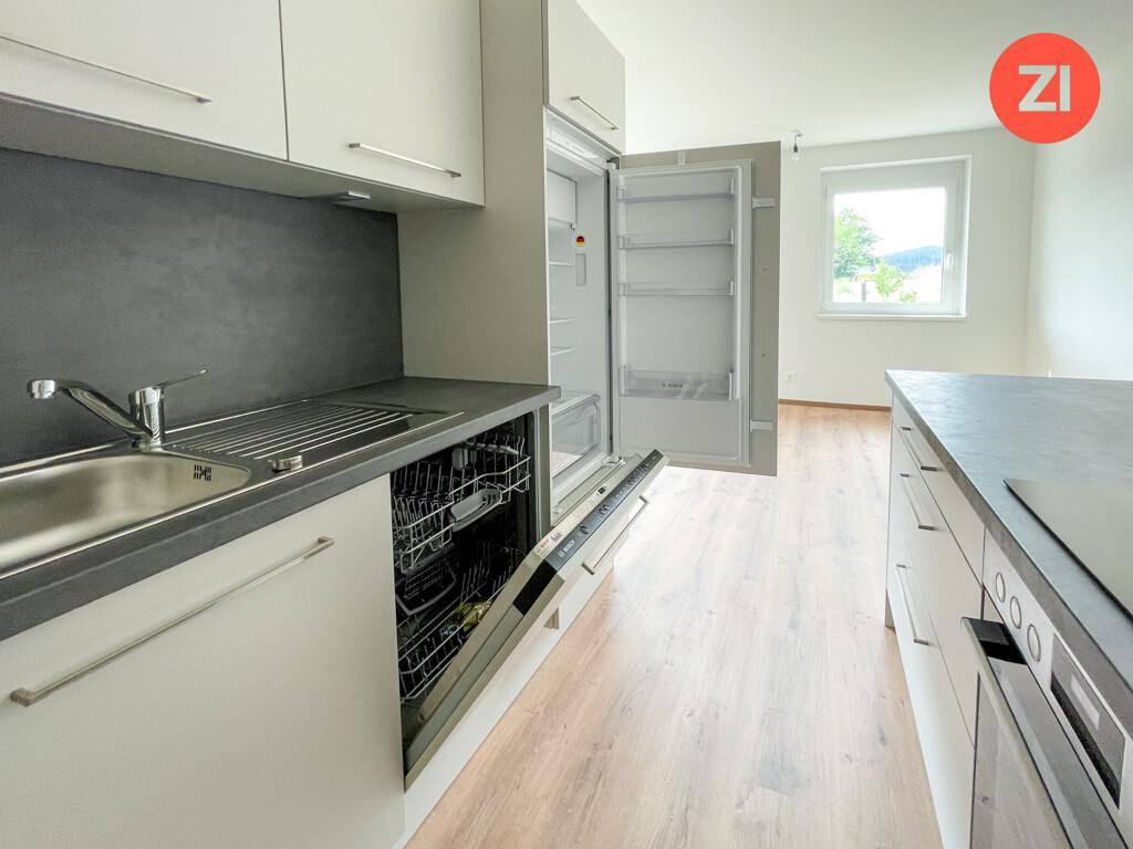 Detailansicht der modernen Küche mit integriertem Geschirrspüler, Kühlschrank und Fensterblick.