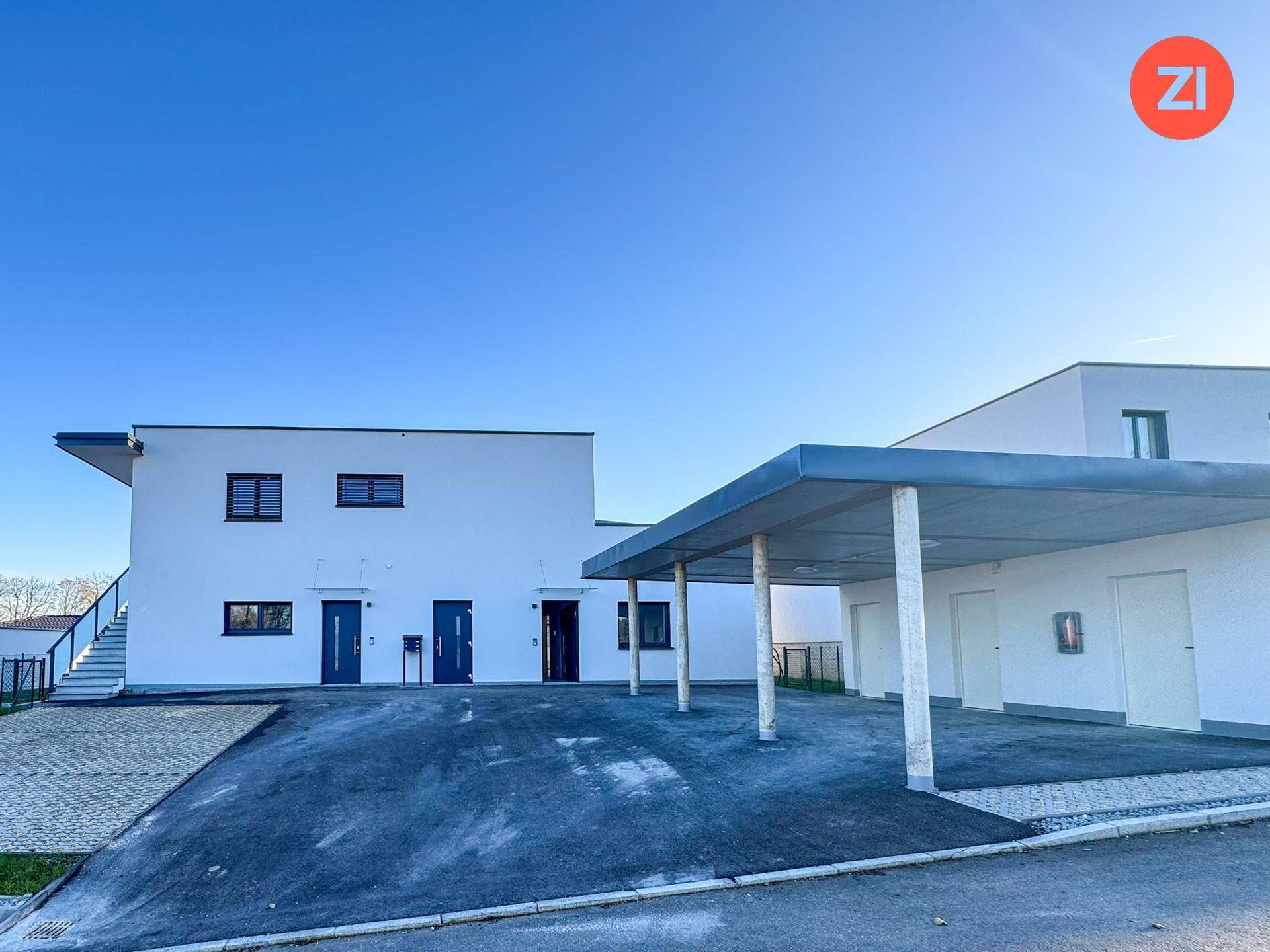 Vorderansicht eines modernen Neubaus mit Carport und mehreren Eingängen.