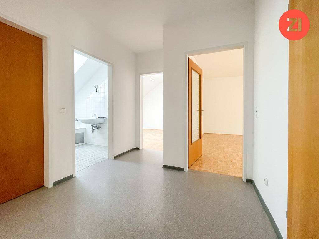 Heller Flur mit grauem Boden, der zu verschiedenen Zimmern und einem Badezimmer führt.