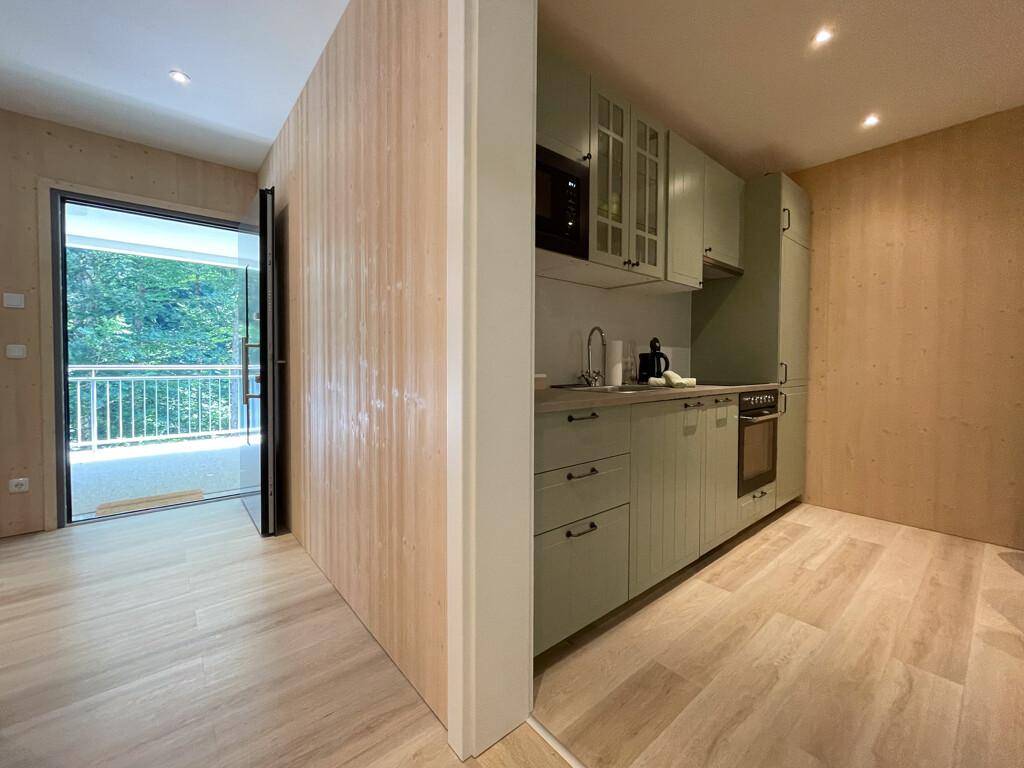 Moderne Küche mit hellgrünen Schränken und direktem Zugang zu einem Balkon.