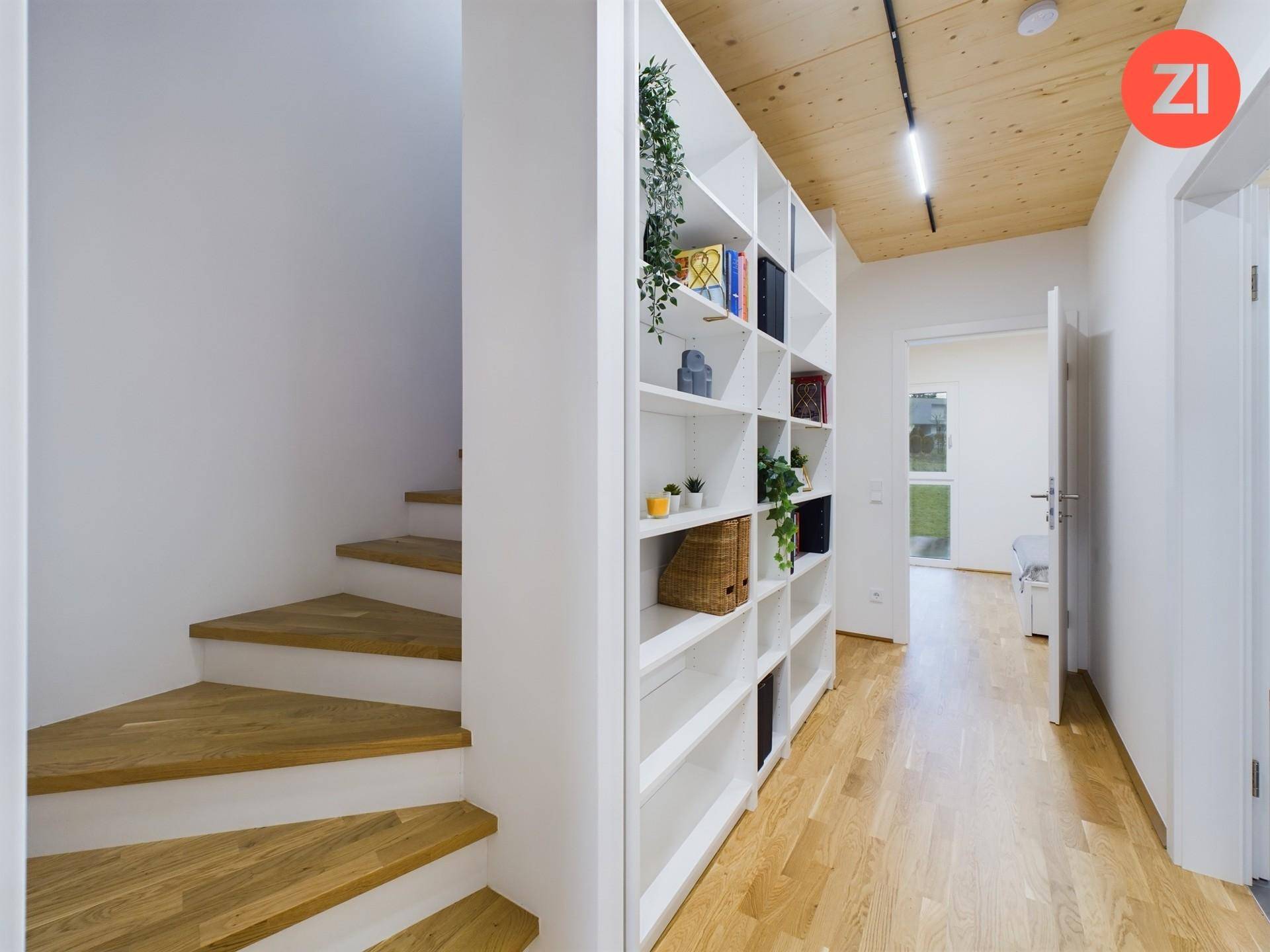 Heller Flur mit Holztreppe, integriertem Bücherregal und Holzboden.