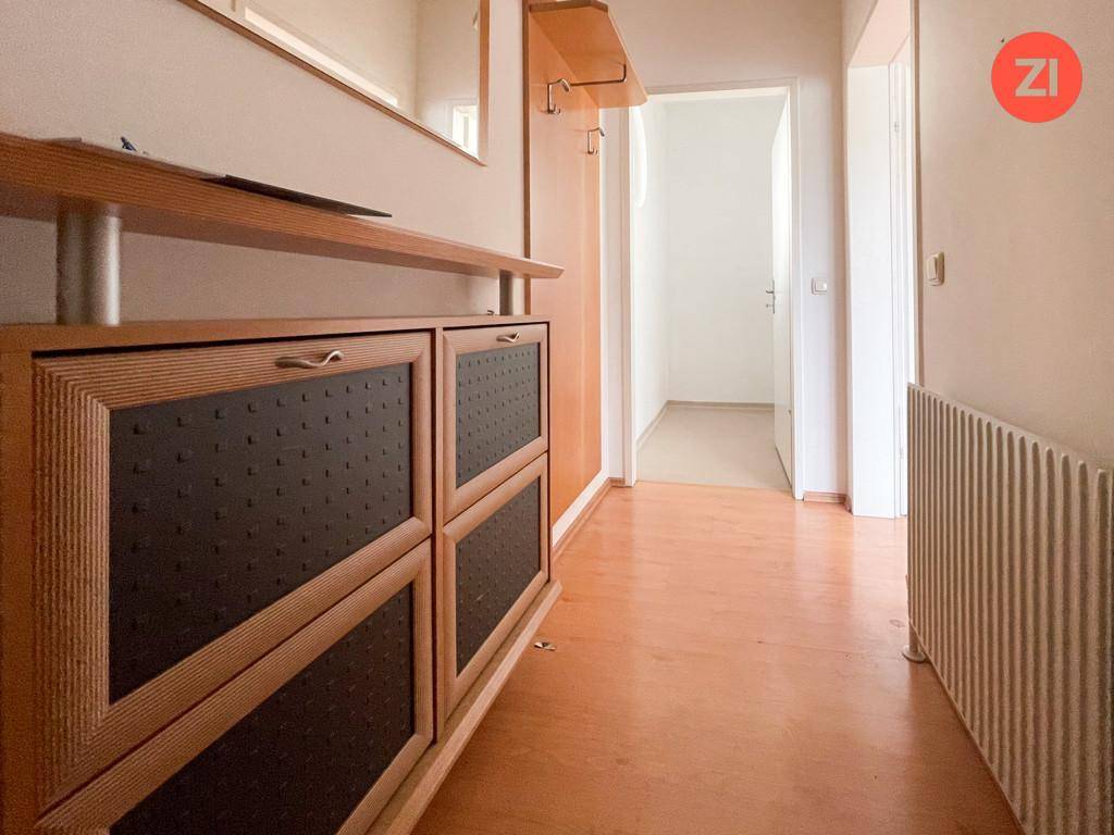 Eingangsbereich mit Holzfußboden und einem Schuhschrank, der zu weiteren Räumen führt.