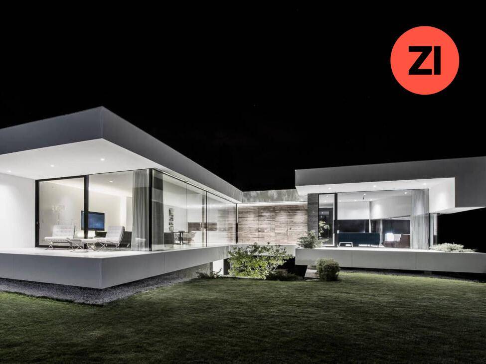 Moderne Architektur der Villa bei Nacht mit beleuchteten Glasfassaden und Garten.