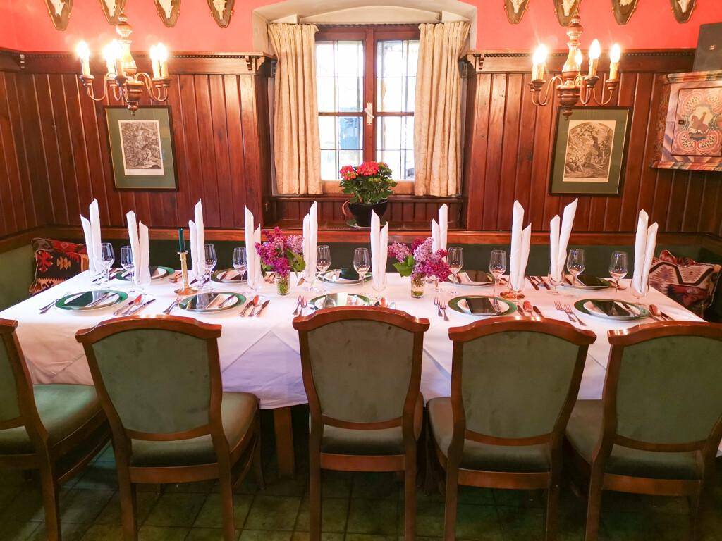 Gemütlicher Speisebereich mit Holztäfelung, traditionellen Möbeln und einem festlich gedeckten Tisch.