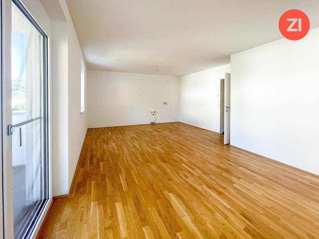 Großer, heller Raum mit Parkettboden und Anschlüssen für eine zukünftige Einbauküche.
