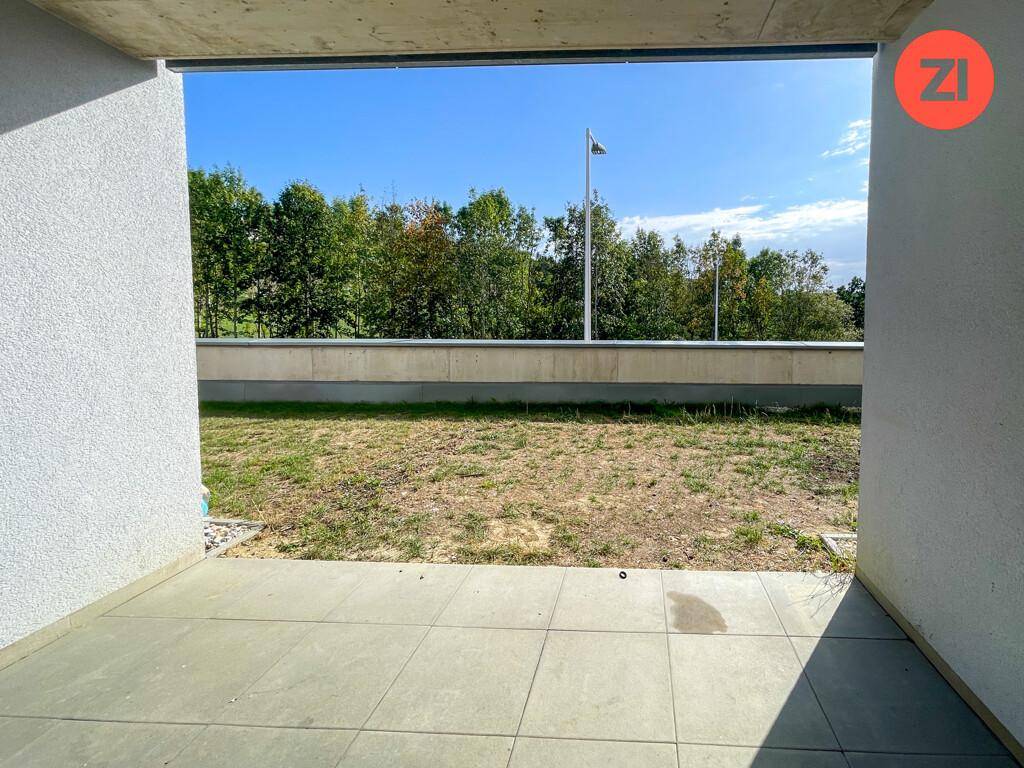 Blick von der gefliesten Terrasse auf den privaten Gartenbereich und die umliegende Natur.