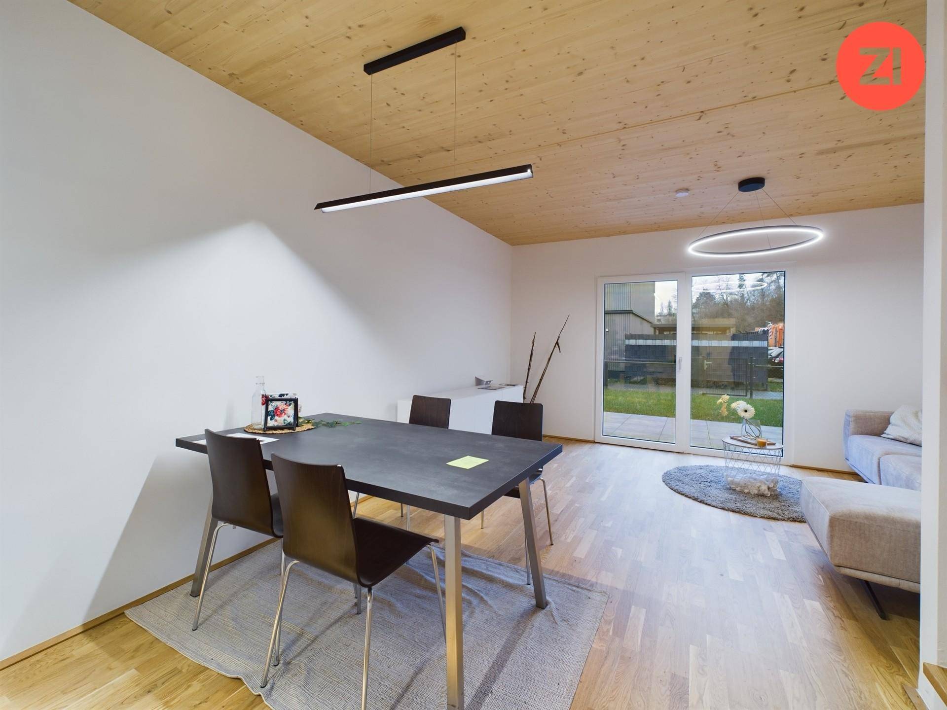 Heller Essbereich mit Holzboden, modernem Esstisch und Blick in den Garten.