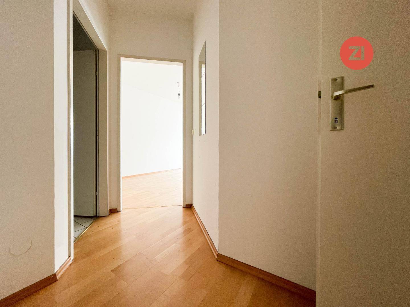 Heller Flur mit Parkettboden, der zu weiteren Zimmern der Wohnung führt.