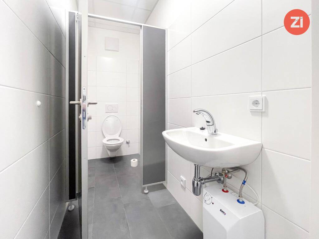 Sauberes WC mit Waschbecken, Toilette und weißen Wandfliesen, gut gepflegt und funktional.