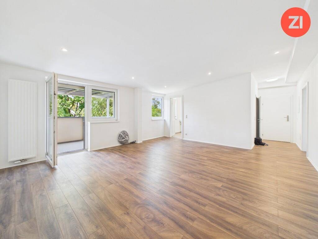 Geräumiges Wohnzimmer mit Laminatboden, weißen Wänden und Zugang zum Außenbereich.