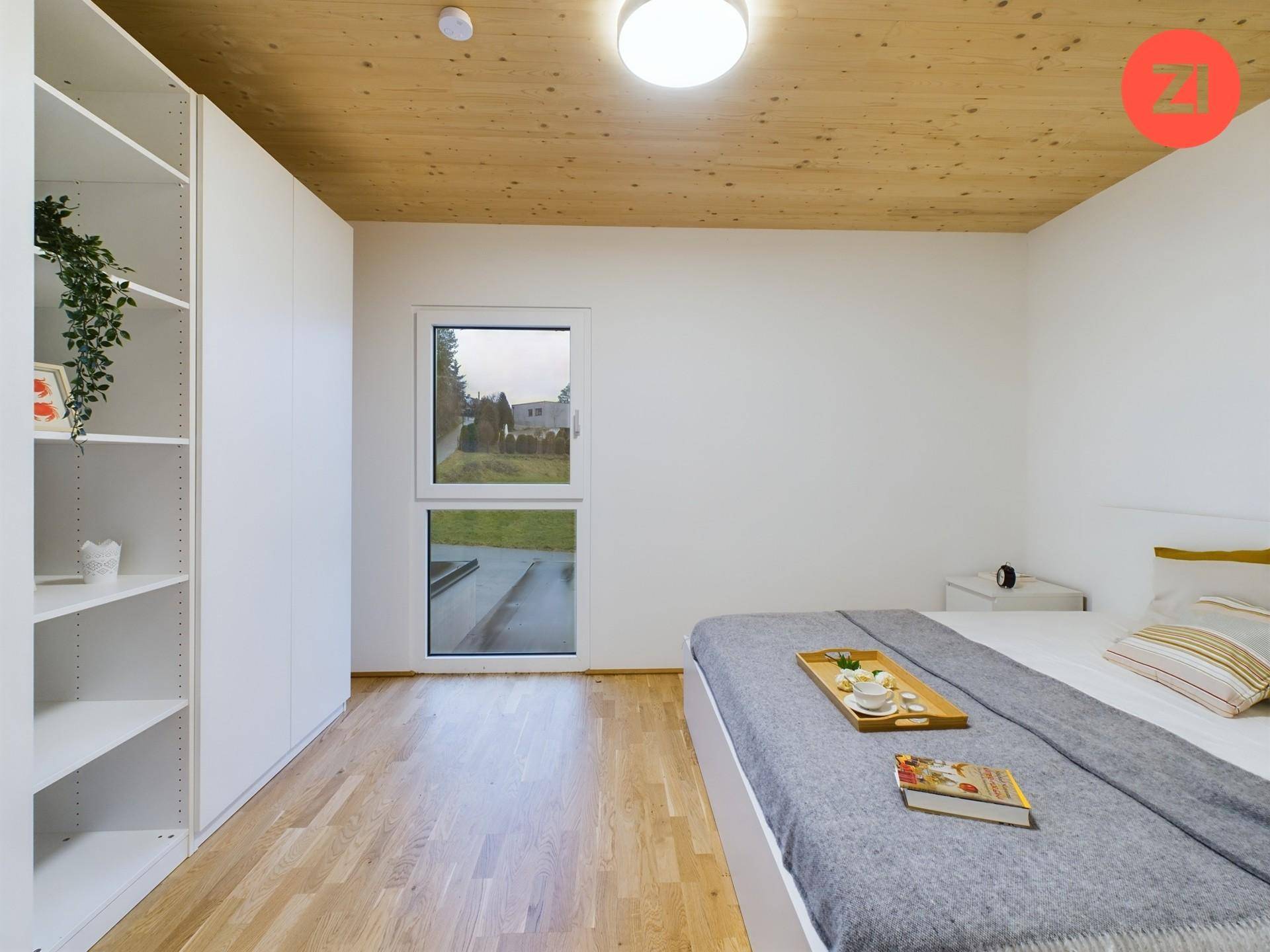 Schlafzimmer mit Holzboden, Einbauschrank und großem Fenster, das viel Tageslicht hereinlässt.