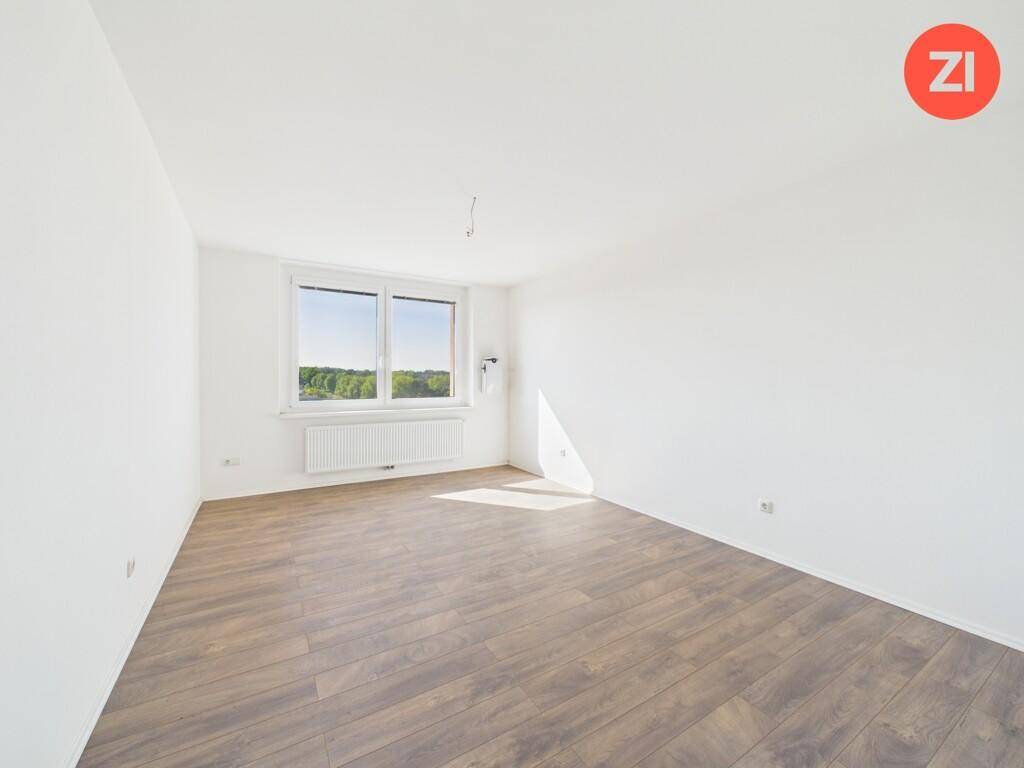 Helles Schlafzimmer mit Laminatboden und weitem Ausblick durch das große Fenster.