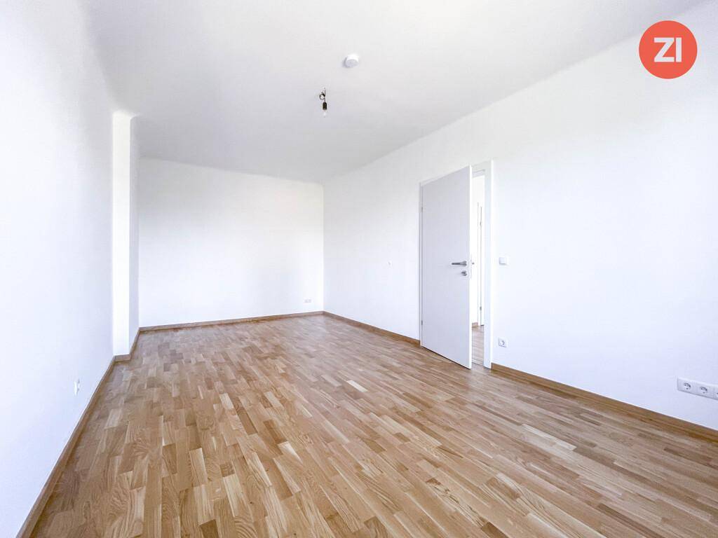 Leerer Raum mit hellem Parkettboden und weißen Wänden, bereit zur individuellen Gestaltung.