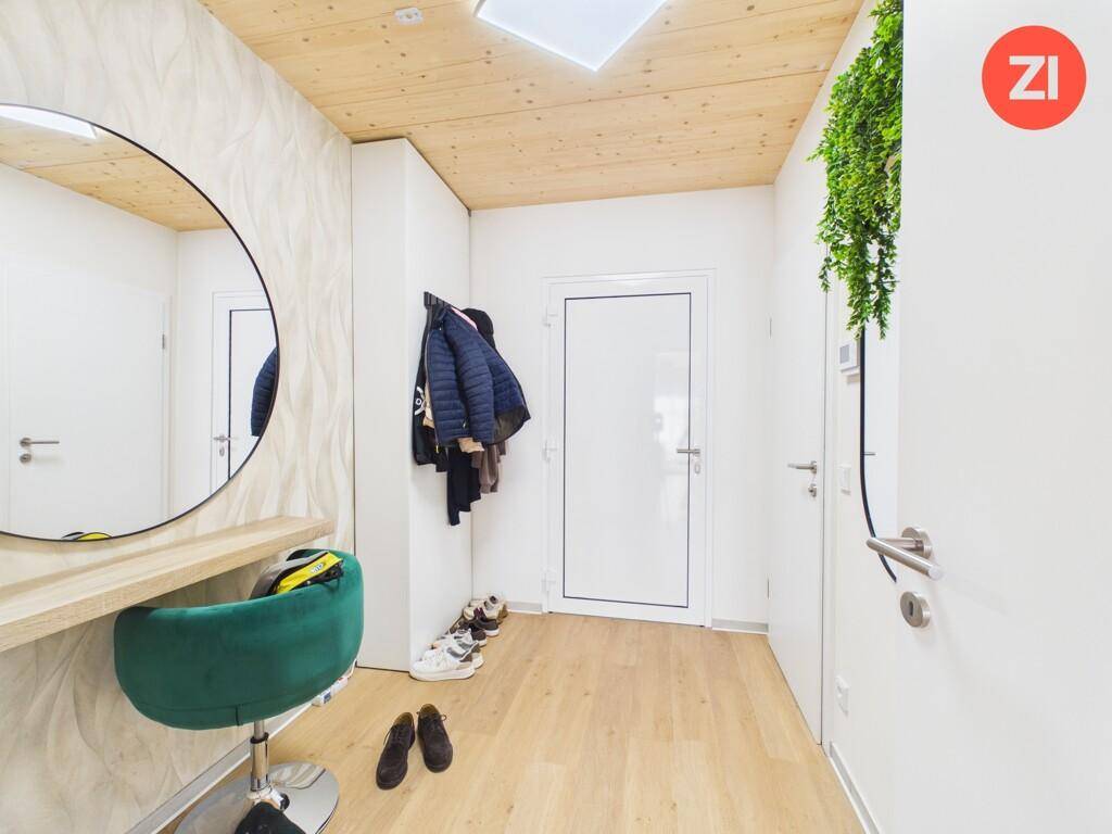Freundlicher Eingangsbereich mit großem Rundspiegel, Holzboden und Garderobe.